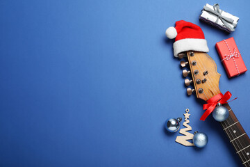 Flat lay composition with guitar and Santa hat on blue background, space for text. Christmas music