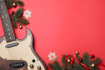 Christmas music. Flat lay composition with guitar and fir tree branches on red background, space...