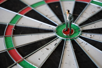 Miniature people, businessman standing on Dart board. Business goals. Picture use for business competition concept or business game concept.