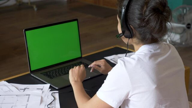 Over the shoulder shot of Asian woman looking at green screen. Office person using laptop computer with green screen
