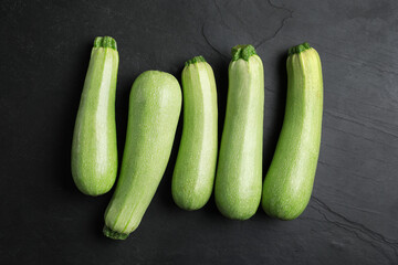 Raw green zucchinis on black slate table, flat lay