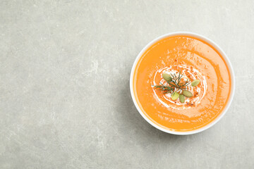 Delicious pumpkin soup in bowl on grey table, top view. Space for text