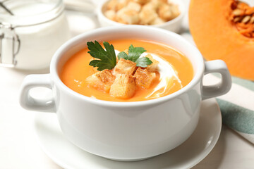 Delicious pumpkin soup served on white table