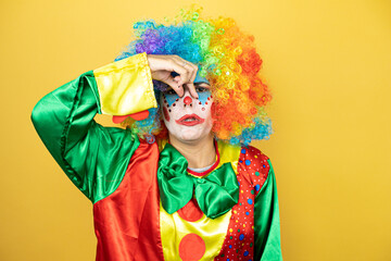 Clown standing over yellow insolated yellow background smelling something stinky and disgusting,...