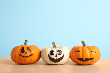 Pumpkins with scary faces on light blue background, space for text. Halloween decor