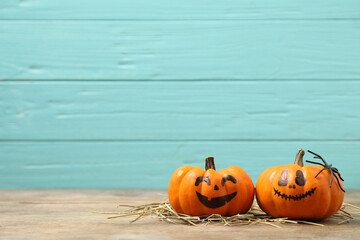 Pumpkins with scary faces on light blue wooden background, space for text. Halloween decor