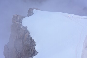 2 personnes équipées de grimpeurs qui marchent dans la neige.  Ils sont attachés par une corde. Pic de montagne.