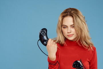 Woman holding in her hands two game controllers entertainment lifestyle red jacket blue background
