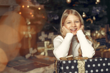 Cute little girl in a white sweater. Child by the christmas tree.