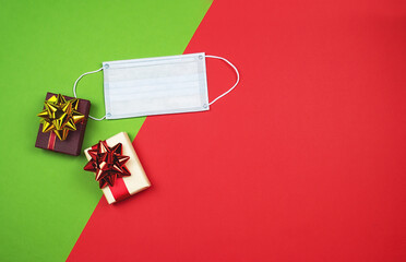 Two gift boxes and a protective medical face mask on a red-green background. Quarantine celebration concept. Christmas and New Year sales. Black Friday. Copy space. Flat lay