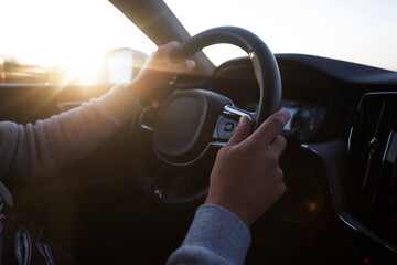 Naklejka premium Success in motion. Handsome young man driving a car at highway during sunset.