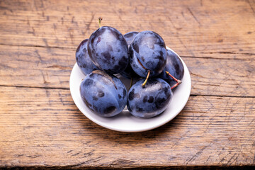 heap of a purple damsons plums over grunge wooden background. natural fruits. healthy eating concept