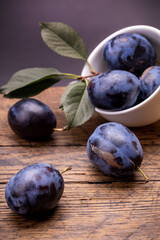 heap of a purple damsons plums over grunge wooden background. natural fruits. healthy eating concept