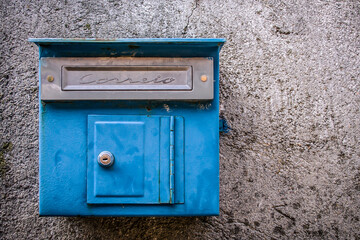 Blue letterbox on a concrete wall in a Portuguese village.