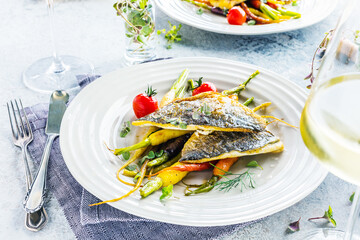  sea fish with rainbow carrot and wine     glasses on bright table. gourmet dissh