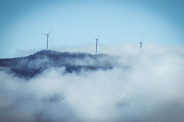 Windmills generating electricity in the clouds / alternative energy / beautiful view.