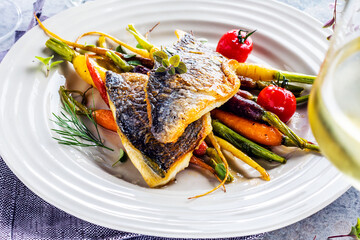  sea fish with rainbow carrot and wine     glasses on bright table. gourmet dissh