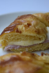 Close up of ham and cheese croissant served on white plate