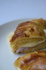 Close up of ham and cheese croissant served on white plate