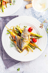  sea fish with rainbow carrot and wine     glasses on bright table. gourmet dissh