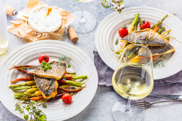  sea fish with rainbow carrot and wine     glasses on bright table. gourmet dissh