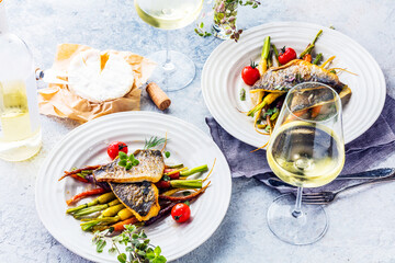  sea fish with rainbow carrot and wine     glasses on bright table. gourmet dissh