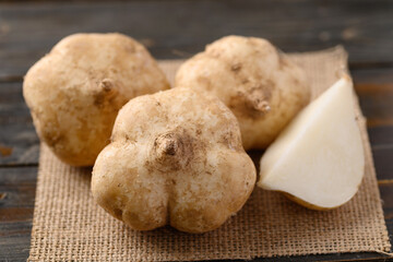 Fresh jicama or yam on wooden table. Jicama can be eaten raw or cooked, The taste are crisp, juicy, moist, and slightly sweet