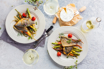  sea fish with rainbow carrot and wine     glasses on bright table. gourmet dissh