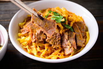 Northern Thai food (Khao Soi), Spicy curry noodles soup with beef in a bowl eating by chopsticks