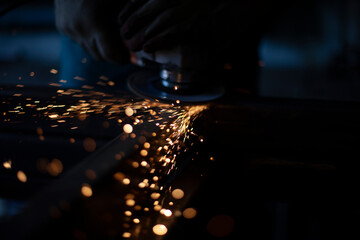 Grinding metal with a grinder. Working in a metal processing workshop. Cleaning the steel seam. The...