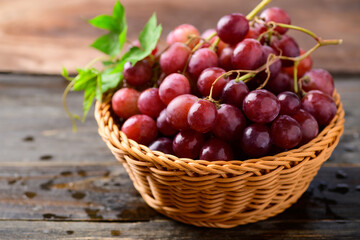Fresh red grapes fruit in a basket on wooden background