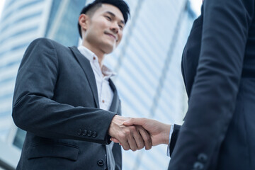 Asian businessmen make handshake in the city with building background.