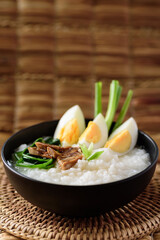 Asian food, Rice soup with boiled egg, grilled mushroom and spinach in a bowl on woven rattan sheet