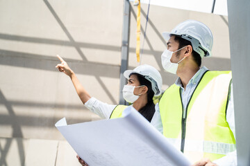 Asian young engineer man and woman looking on drawing and explaining.