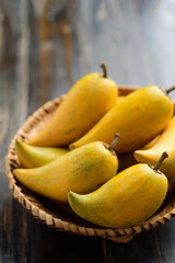 Eggfruit or canistel in a basket on wooden table, Thai fruit, In Thai names such as Xiantao, Lamut Khamen or Mon khai
