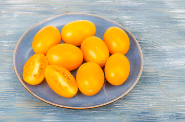 Blue plate with ripe yellow tomatoes. Photo