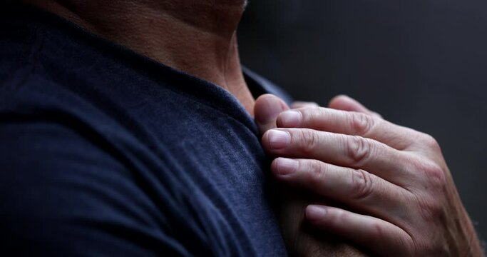 Senior man feeling awe and presence of God, spiritual person with hand in chest praying