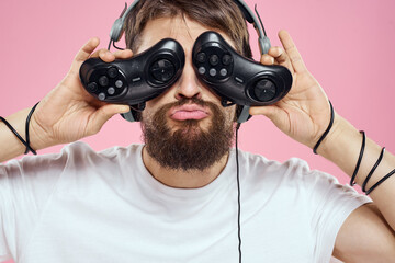 Man in headphones with joysticks in hands playing games lifestyle fun entertainment pink background