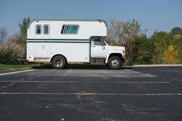 Fototapeta na wymiar Vintage white and green horse trailer van in parking lot