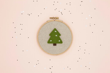 Christmas tree with embroidery frame on pink background.