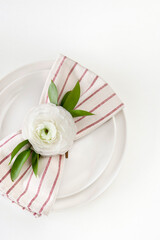 Dinner place setting with white ranunculus.