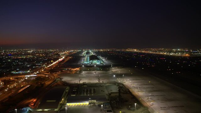 An amazing aerial view of Dubai airport night view. wide-angle parallax around the airport full of lights and color 6-axis stabilized gimbal, Shotover F1, 8K, zoom in and out, parallax,