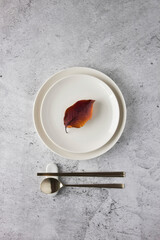 Table setting with fallen leaf on tile background.