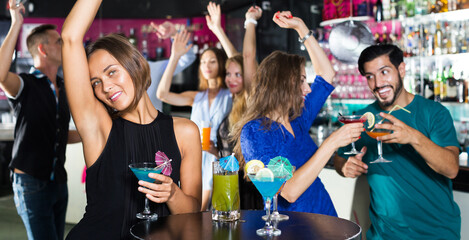 Female is dancing and drinking cocktail on the party in bar.