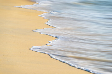 Soft wave of the sea on the sand beach for the background.