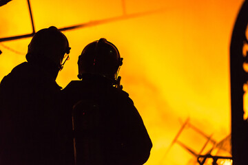 Flames and smoke rise from burning building.