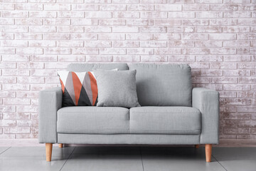 Stylish sofa near brick wall in room