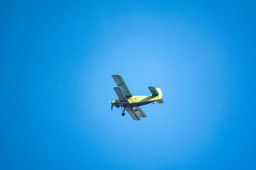 Retro green biplane plane in the blue sky