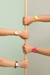 Female hands with watches holding wooden stick on color background