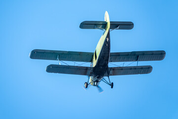 Retro green biplane plane in the blue sky